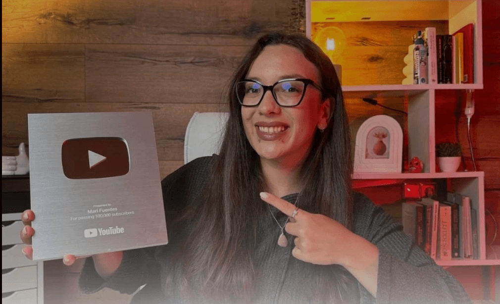 Emprendedora digital mostrando una placa de YouTube por alcanzar más de 100.000 suscriptores en su canal